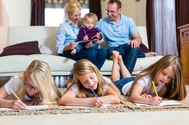 Familia en casa, los niños coloreando en el piso