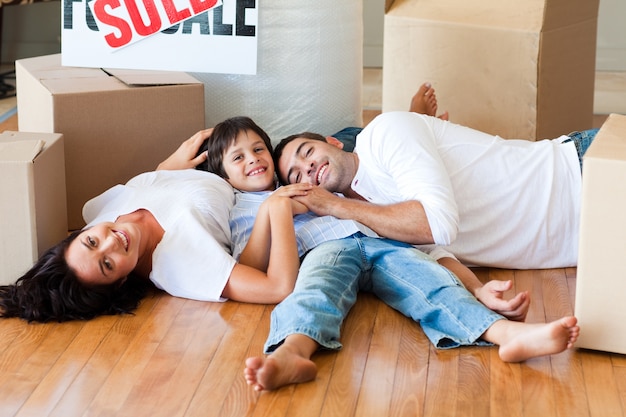 Familia en una casa nueva acostada en el piso con cajas