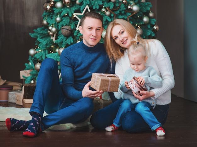 família caucasiana pai mãe e filha perto da árvore de natal em casa interior