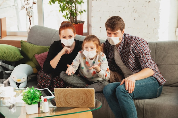 Foto familia caucásica en máscaras protectoras y guantes aislados en casa