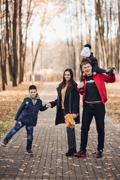 Familia caucásica sale a pasear por el parque de otoño con dos hijos