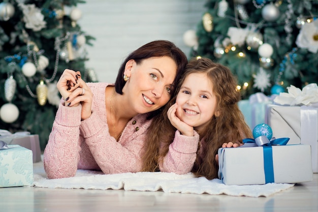 La familia celebra la Navidad. Feliz madre con hija. Compartir regalos de Navidad en el plan principal. Feliz Navidad y felices fiestas. Ternura, cuidado y comprensión mutua.