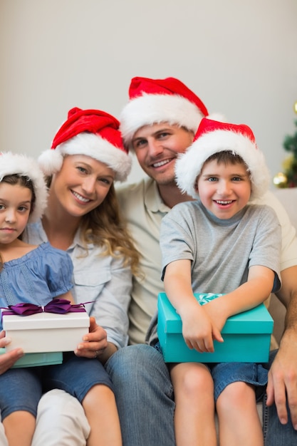 Familia en la celebración de sombrero de Navidad presenta en sofá