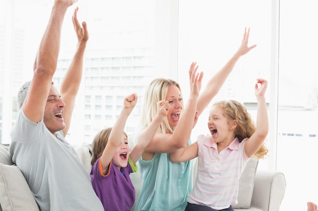 Familia celebrando el éxito mientras ve la televisión