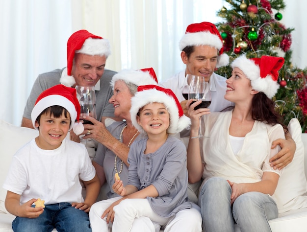 Familia celebrando la Navidad con vino y dulces en casa