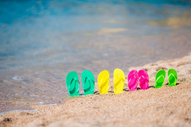 Família colorida flip flops na praia em frente ao mar