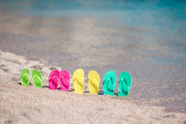 Familia coloridas chanclas en la playa frente al mar