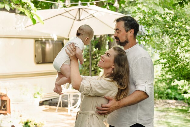 Família com bebê passando momentos felizes juntos perto do trailer, estilo de vida viajando com trailer