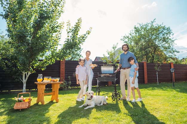 família com cachorro fazendo churrasco juntos no quintal em dia de verão