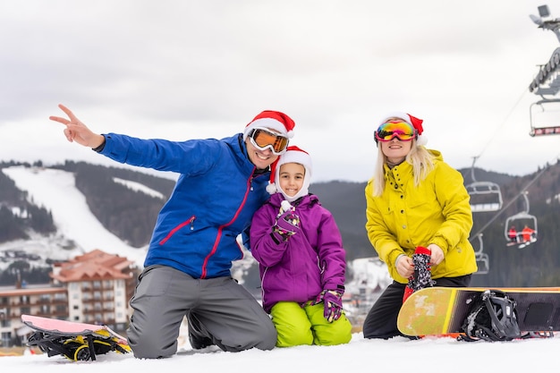 Família com chapéus de papai noel e pranchas de snowboard