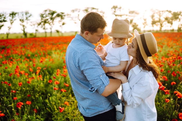 Família com criança caminhando no campo de papoulas mãe pai filha pequena se divertindo no campo de papoulas