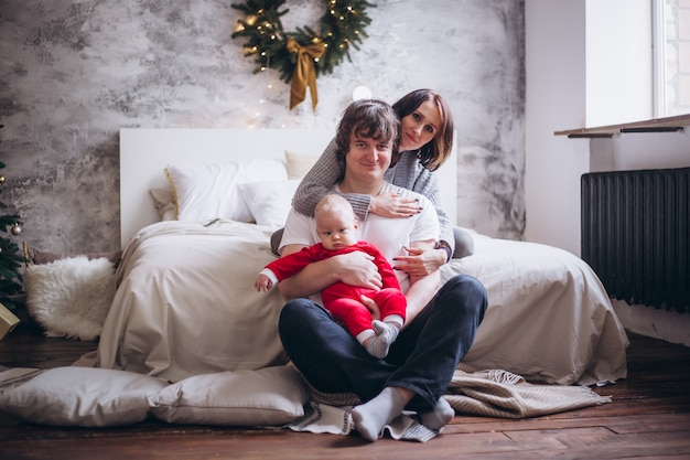 Família com criança em casa na cama perto de árvore de Natal