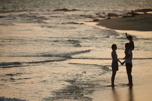 Família com criança em pé na praia