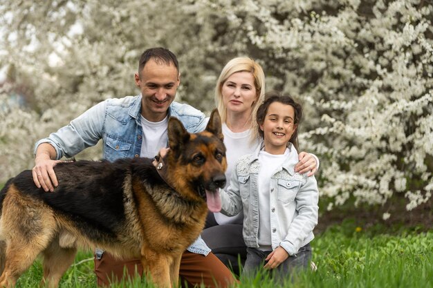 Família com criança pequena e cachorro ao ar livre no pomar na primavera.