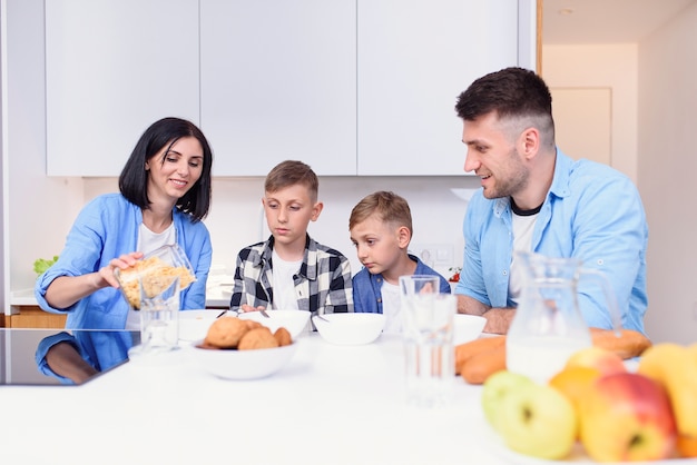 Família com dois filhos tomando café da manhã saudável com cereais e leite