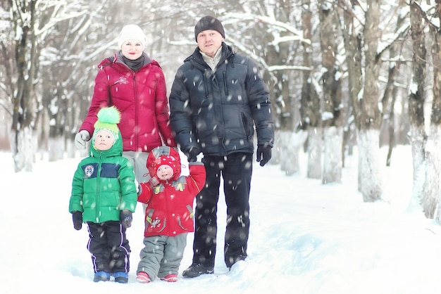 Família com filhos no parque durante nevasca de inverno