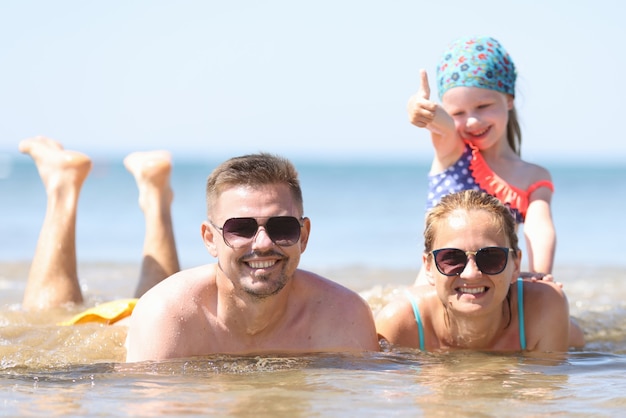 Família com menina deitada no mar