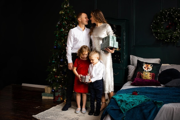 Foto família com presentes em casa pais e filhos se divertindo perto da árvore de natal dentro de casa