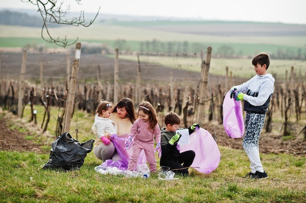 Família com saco de lixo coletando lixo durante a limpeza nas vinhas Conservação ambiental e reciclagem ecológica