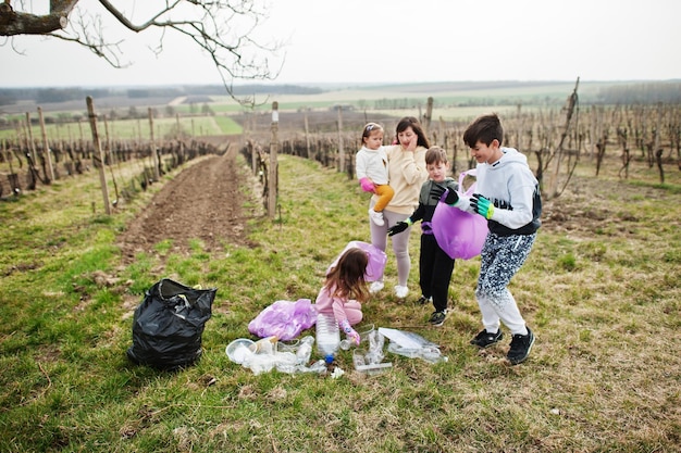 Família com saco de lixo coletando lixo durante a limpeza nas vinhas Conservação ambiental e reciclagem ecológica