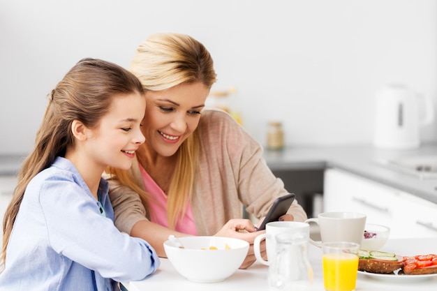 Foto família com smartphone a tomar o pequeno-almoço em casa