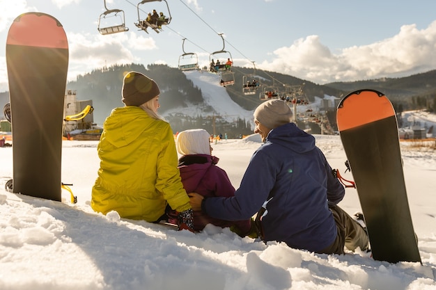 família com snowboards em resort de inverno