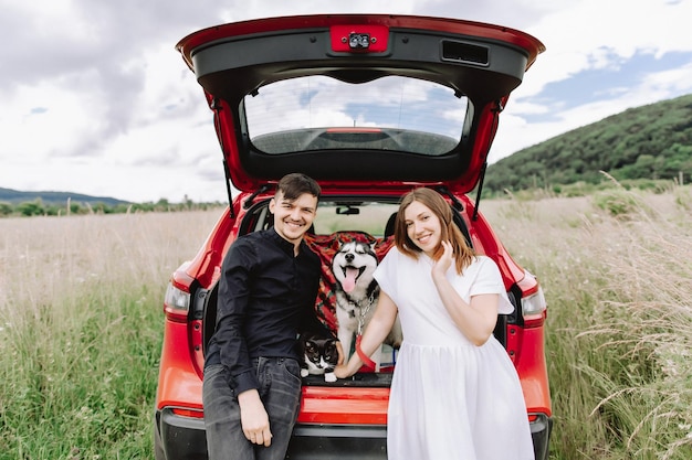 Família com um gato e um cachorro na natureza no fundo de seu carro