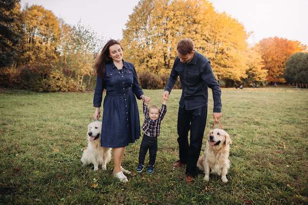 Família com uma criança e dois retrievers dourados em um parque de outono