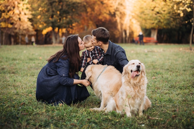 Família com uma criança e dois retrievers dourados em um parque de outono