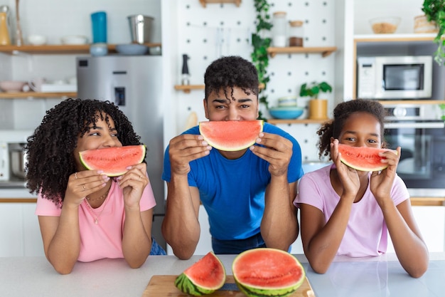 Familia come una sandía dulce en la cocina Un hombre y una mujer con su hija comen una sandía madura en la cocina Familia feliz comiendo sandía