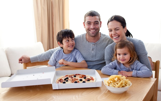 Foto família comendo pizza e batatas fritas em um sofá