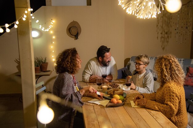 Foto familia comiendo y bebiendo en la mesa en la terraza por la noche