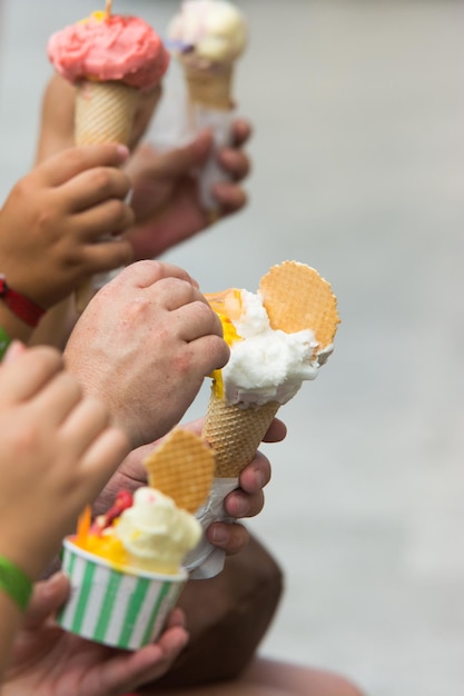 Familia comiendo un helado sentado en la calle detalle de las manos