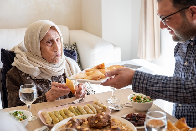 Familia comiendo juntos con miembros de varias generaciones en una sala de estar moderna