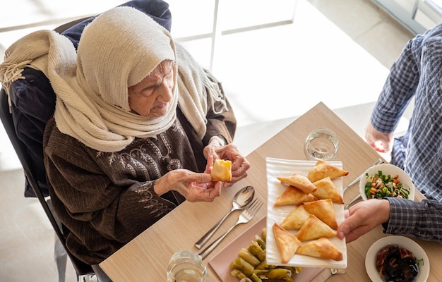 Familia comiendo juntos con miembros de varias generaciones en una sala de estar moderna