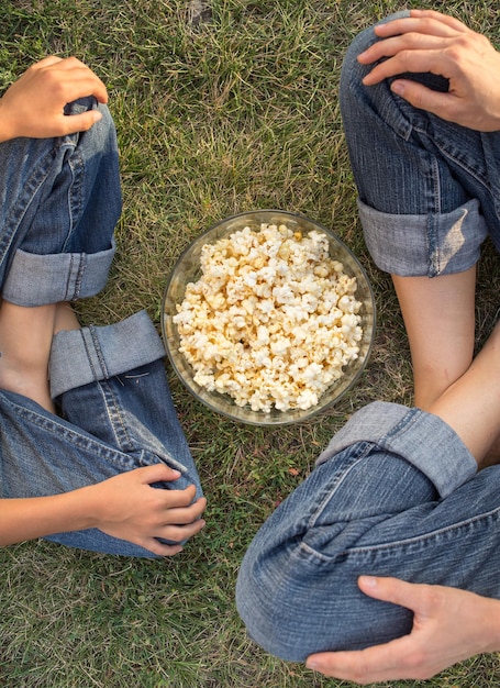 familia comiendo palomitas de maíz sentada sobre hierba verde al revés