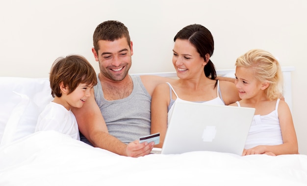 Familia comprando en línea en la cama