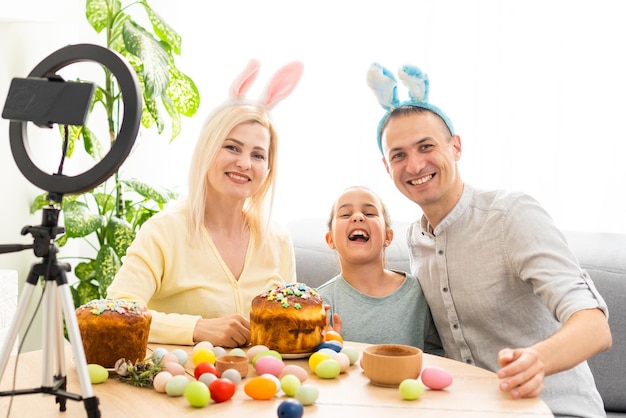 la familia se comunica en línea usando un programa especial con amigos en las vacaciones de Semana Santa. Conferencia web a través de videollamada en tableta a sus colegas. Mesa decorada con flores y huevos de colores.