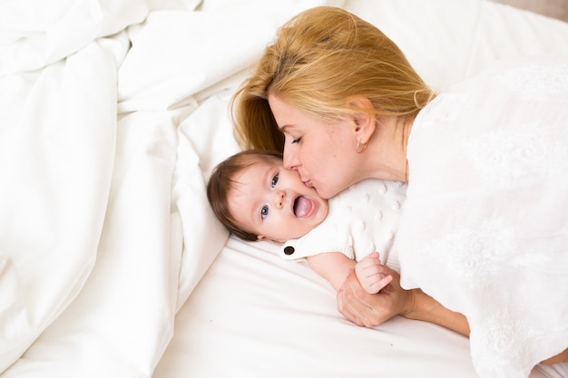 Familia, concepto de mañana de crianza. bebé feliz con la madre en la cama en casa