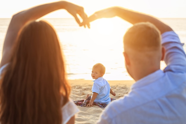 Familia en el concepto de playa, caucásico emplazamiento de niño y la celebración de arena en la playa tropical en el atardecer