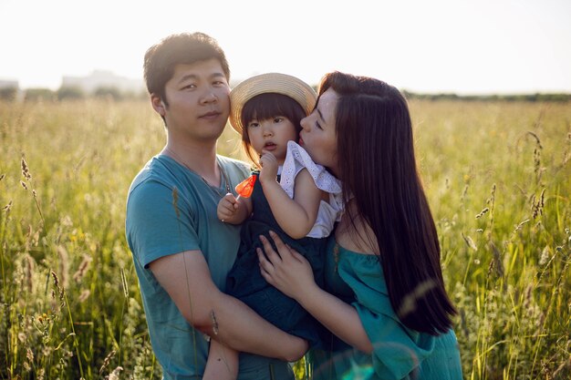 Família coreana com sua filha vai para o campo na grama ao pôr do sol