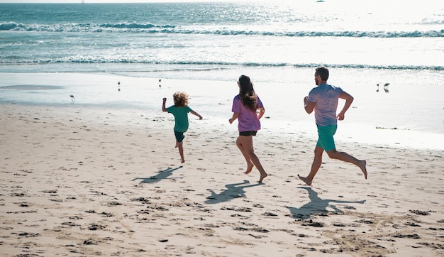 Família correndo em um conceito de praia de areia de família amigável correndo ao ar livre pais ativos e pessoas