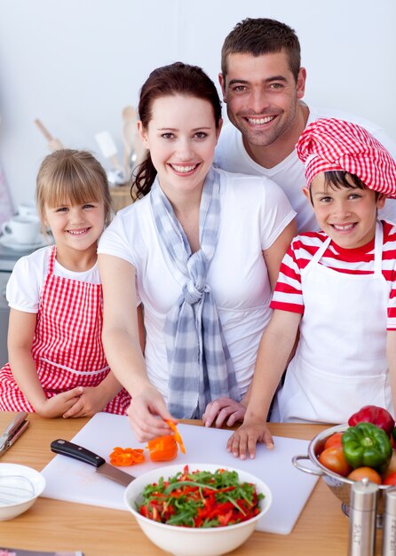 Família cortando pimentas coloridas na cozinha