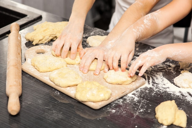 Família, cozinhar bolos caseiros, as mãos da mãe e filha em farinha sobre uma mesa