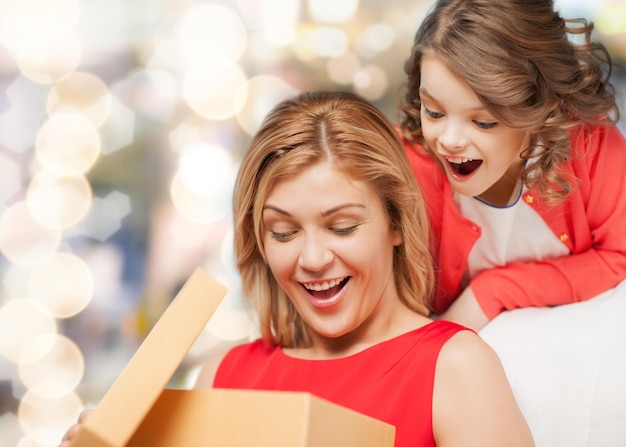 família, criança, feriado e festa - sorrindo mãe e filha com caixa de presente