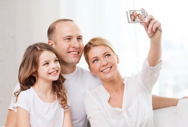 família, criança, fotografia e conceito de casa - família feliz com garotinha fazendo autoretrato com câmera digital