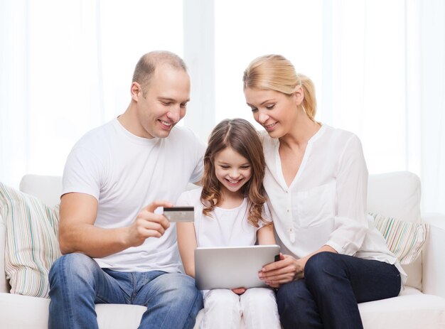 família, criança, tecnologia, dinheiro e conceito de casa - pais sorridentes e menina com tablet pc e cartão de crédito em casa