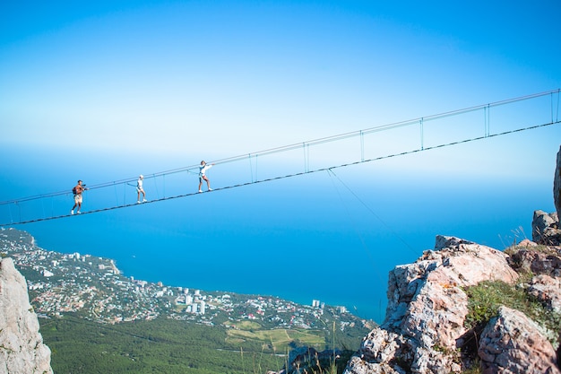 Família cruzando o abismo na ponte de corda fundo do mar negro na Crimeia na Rússia