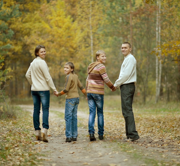 Familia de cuatro en el bosque de otoño, vista posterior