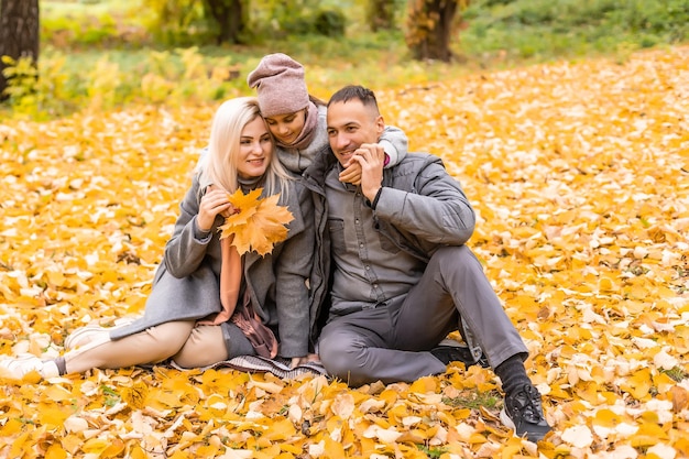 Una familia de cuatro disfrutando de hojas doradas en el parque de otoño